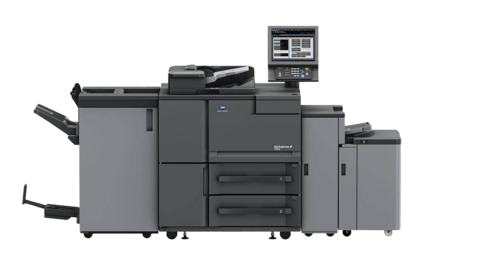 MODOX PRINT FOX High Volume Nahaufnahme einer sich schnell bewegenden industriellen Druckmaschine, in der bunte Papierbögen schnell durch große schwarze Walzen laufen. Die gedruckten Bilder erscheinen aufgrund der Geschwindigkeit der Maschine unscharf.