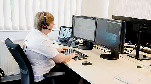 MODOX-Supportmitarbeiter sitzt an einem Pc und telefoniert mit Headset