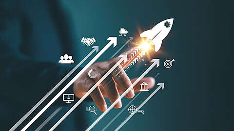 Ein Zukunftsausblick: Weiterentwicklung der digitalen Technologien Eine Hand zeigt auf ein leuchtendes Raketensymbol, das Innovation und Wachstum symbolisiert. Um die Rakete herum befinden sich Symbole wie ein Händedruck, eine Wolke, ein Ziel, ein Computer, drei Köpfe und ein vernetzter Globus. Weiße Pfeile zeigen nach oben und symbolisieren Fortschritt und Entwicklung.