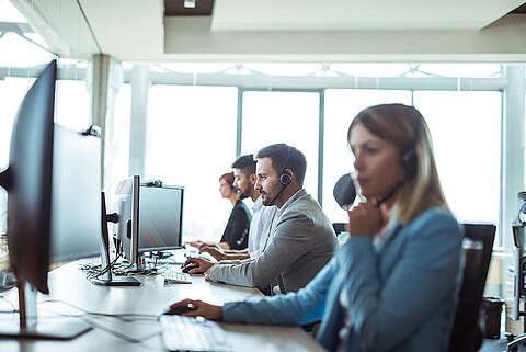 Servicemitarbeiter sitzen in einem Büro und telefonieren mit Kunden